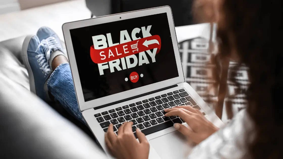 Person shopping online for Black Friday deals on a laptop, highlighting a 'Black Friday Sale' banner.