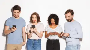 A diverse group of people individually engaged with their smartphones, illustrating the widespread digital connectivity and consumer behavior that digital marketing targets during economic uncertainty.