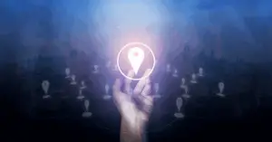 Hand reaching up to a glowing location pin with a city skyline backdrop, connected by network lines.