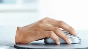 A hand using a computer mouse, symbolizing the process of turning clicks to clients** and mapping marketing strategy back to ROI.