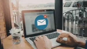 A person typing on a laptop with an email notification icon, representing effective CRM follow-up and marketing automation using RevStream.