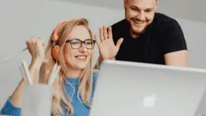 A smiling sales team collaborating over a laptop, demonstrating how RevStream CRM automation replaces manual spreadsheets to improve marketing ROI and team efficiency.